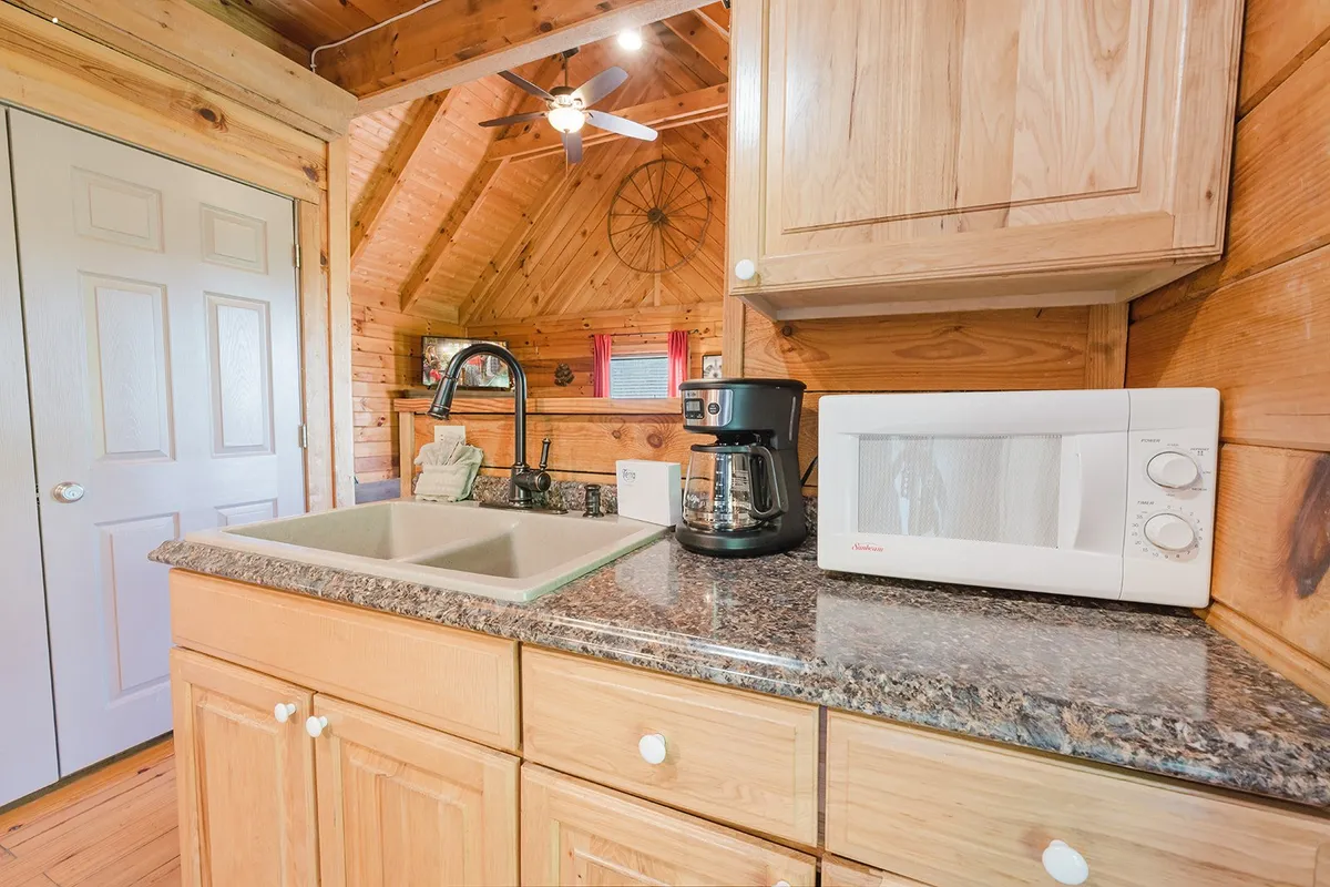 A bright, homely kitchen corner featuring a granite countertop, sink, coffee maker, microwave, and wooden cabinetry. The space feels both modern and comforting, inviting guests to brew their morning coffee or prepare breakfast together.