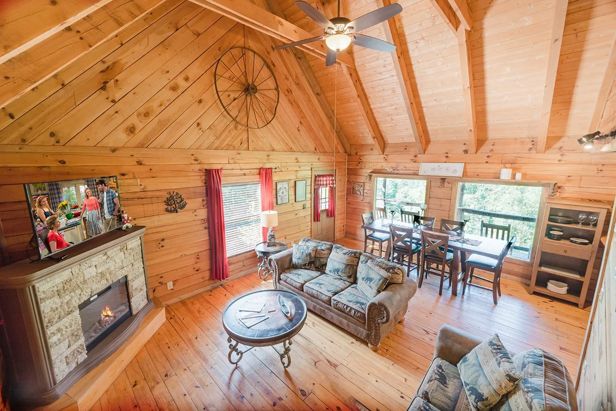 A spacious living and dining area with a soft sofa, dining table, fireplace, and wide windows that frame picturesque views. The room is designed for family gatherings and game nights, with ample space for pets and guests to mingle.