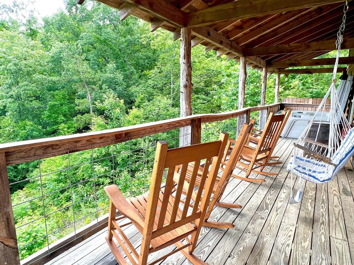 A spacious deck with wooden rocking chairs and a hammock overlooking vibrant greenery. The area is shaded and inviting, ideal for relaxing after a day outdoors with your pup. The space hints at shared moments soaking in the mountain air.